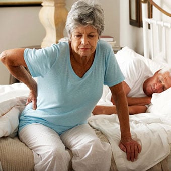 A woman experiencing discomfort from kidney stones in her lower back and side.